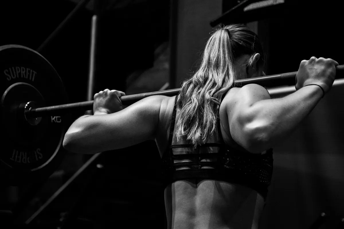 Femme en position de squat avec une barre sur le dos